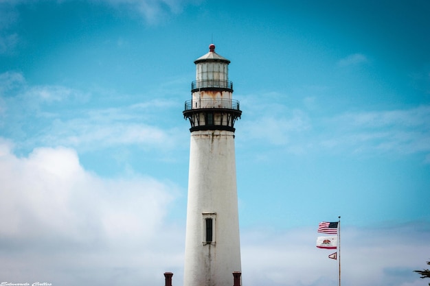 low angle view of lighthouse and flags against sky