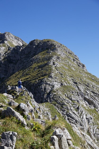 明るい空を背景に山を登る男の低角度の写真