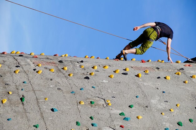 Foto vista a bassa angolazione di un uomo che si arrampica sul muro contro il cielo