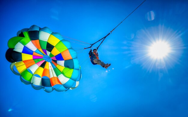 Low angle view of man enjoying parasailing against blue sky