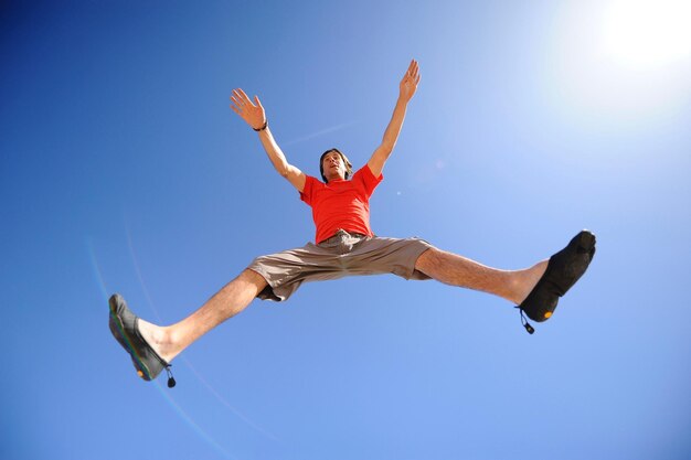 Low angle view of man jumping against blue sky