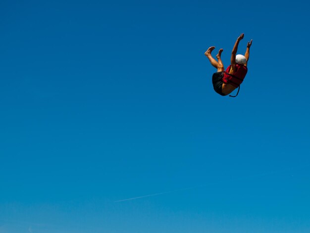 Photo low angle view of man jumping against clear blue sky