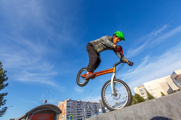 Foto vista a bassa angolazione di un uomo che esegue una acrobazia in bicicletta contro il cielo