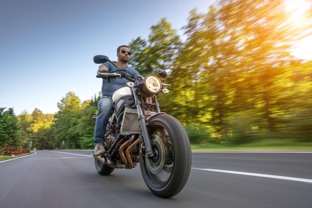 Low angle view of man riding motorcycle on road against trees