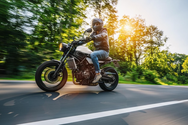 Low angle view of man riding motorcycle on road against trees