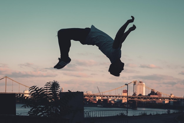 夕暮れの空に照らしてスケートボードをしている男の低角度の景色