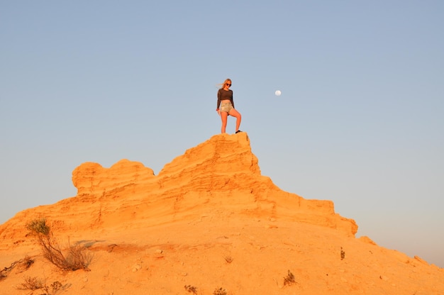 Photo low angle view of man standing on rock against sky