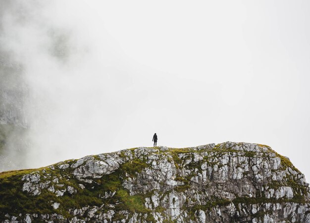 Photo low angle view of man standing on rock against sky