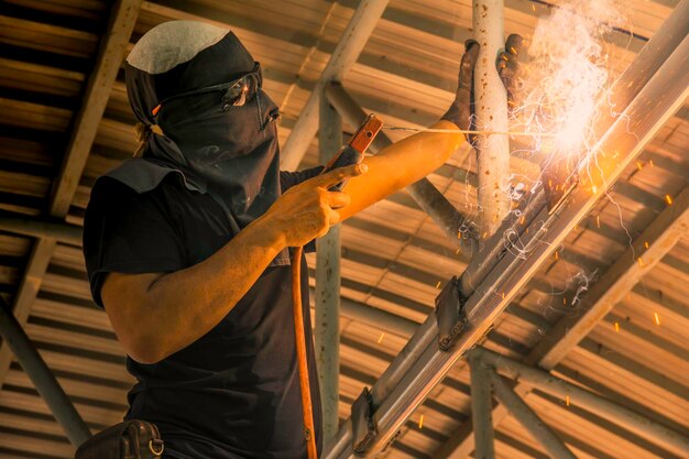 Photo low angle view of man welding in factory