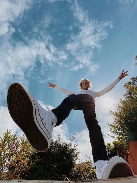 Photo low angle view of man with arms raised against sky