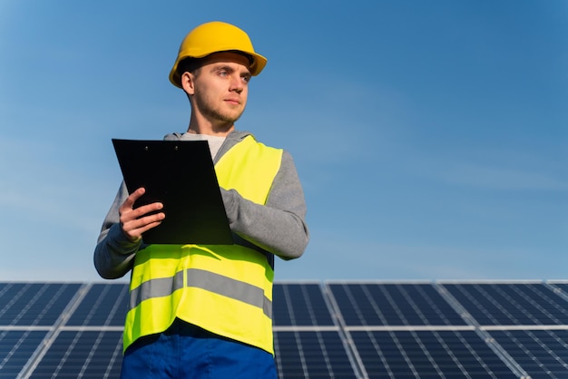 Low angle view of the man worker handwriting agenda take notes
at the solar panels industrial area green energy concept