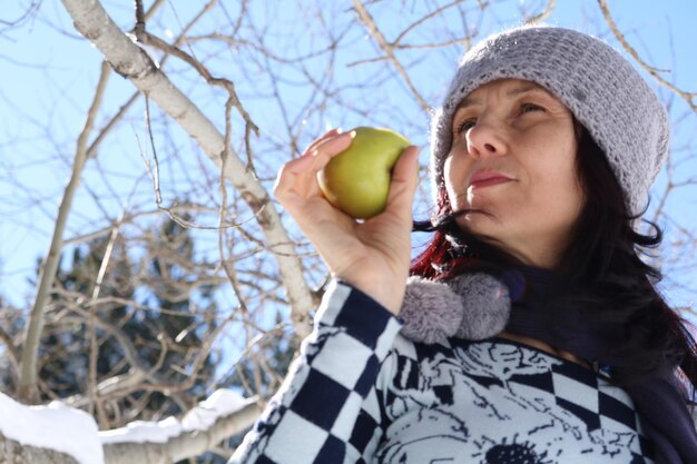 Low angle view of mature woman holding fruit