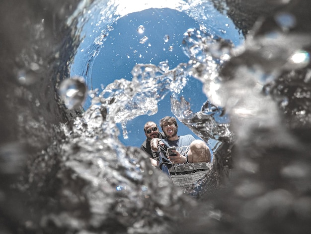 Foto vista ad angolo basso di uomini che si fanno un selfie con un monopode in acqua