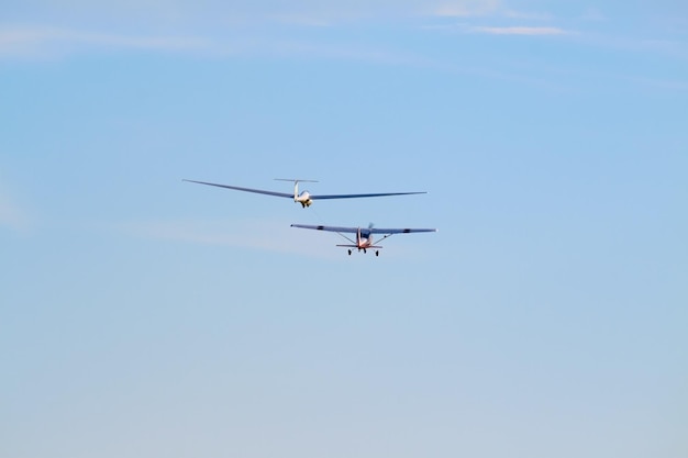 青い空に向かって飛ぶ軍用ドローンと飛行機の低角度の景色