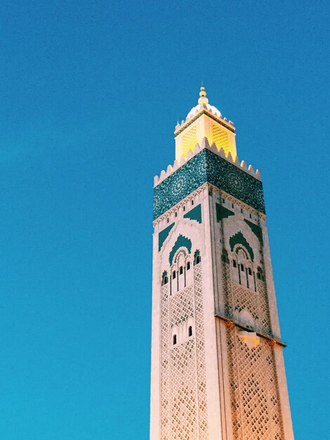 Low angle view of minaret against clear blue sky