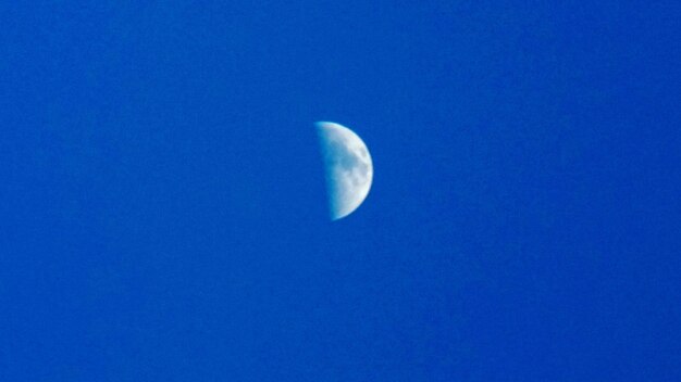 Low angle view of moon against clear blue sky