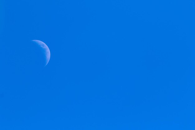 Low angle view of moon against clear blue sky