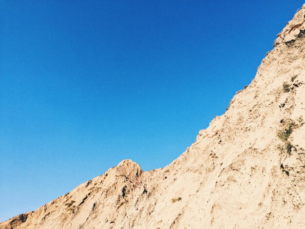 Low angle view of mountain against clear blue sky