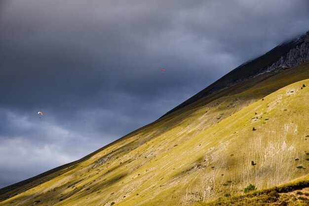 Foto vista a basso angolo della montagna contro il cielo con i parapendio a castelluccio umbria in italia