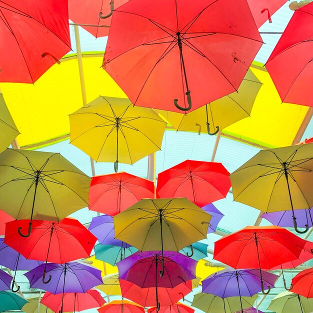 Low angle view of multi colored umbrellas hanging against sky