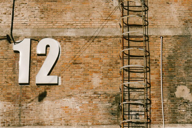 Low angle view of numbers by ladder on brick wall