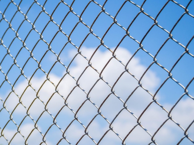 Фото Низкоугольный вид голубого неба через цепной забор