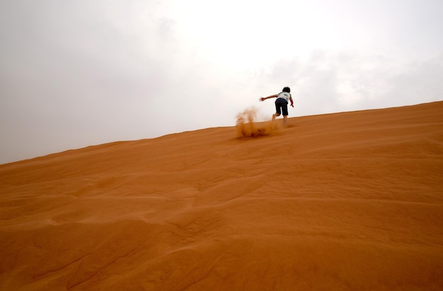 Фото Низкий угол зрения мальчика, бегущего в пустыне