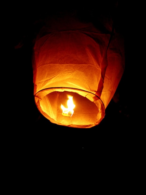 Фото Низкоугольный вид горящего бумажного фонаря, поднимающегося ночью