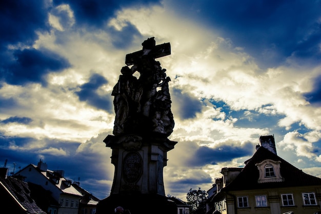 写真 街の雲の空に照らされた十字架と建物の低角度の景色