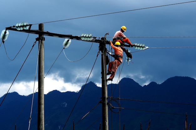 写真 電気柱で働く電気技師の低角度の視点