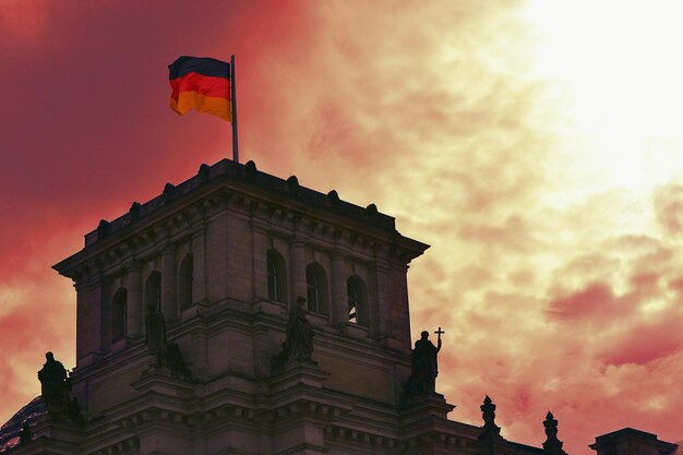 Фото Низкоугольный вид немецкого флага на историческом здании на облачном небе