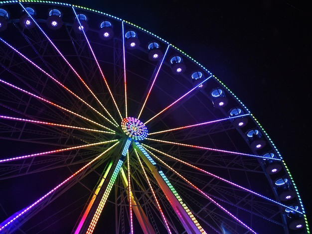 写真 夜の空に照らされたフェリスホイールの低角度の景色