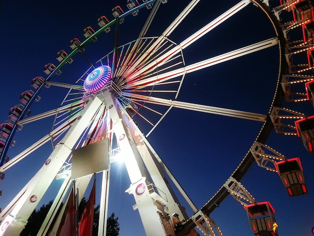 写真 夜の空に照らされたフェリスホイールの低角度の景色