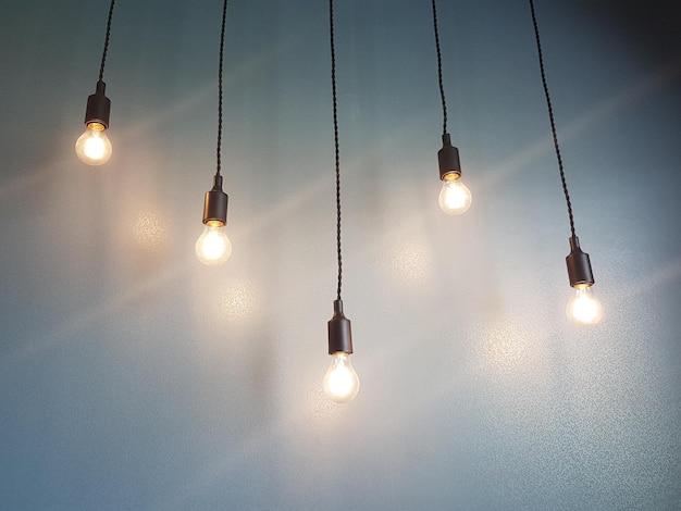 Фото Низкоугольный вид освещенных лампочек, висящих на стене