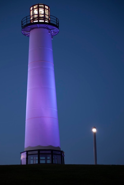 写真 夕暮れの澄んだ青い空に照らされた灯台の低角度の景色