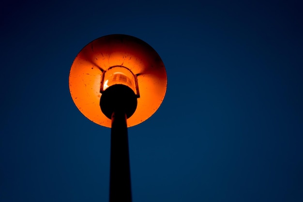 Фото Низкоугольный вид освещенного уличного фонаря на фоне ясного неба ночью