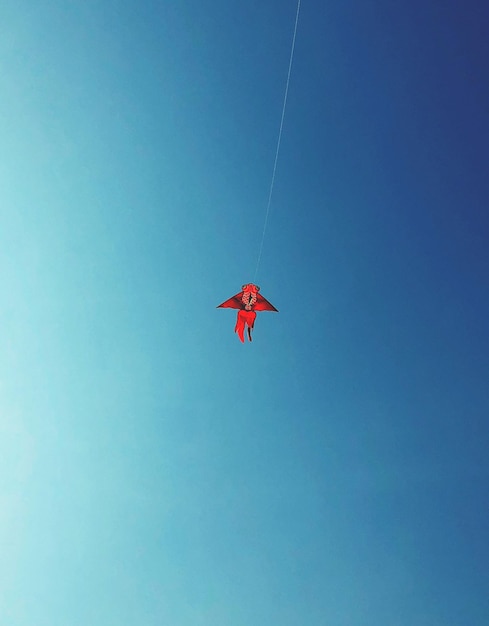 Фото Низкоугольный вид воздушного змея, летящего на чистом голубом небе