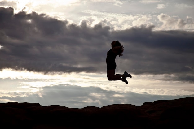 写真 雲の空に飛び込む男の低角度の写真