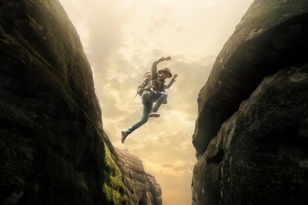 写真 空に向かって岩の形成をジャンプする男の低角度の景色