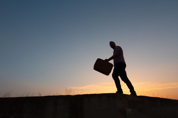 写真 夕暮れの空に向かって陸上を歩く男の低角度の景色