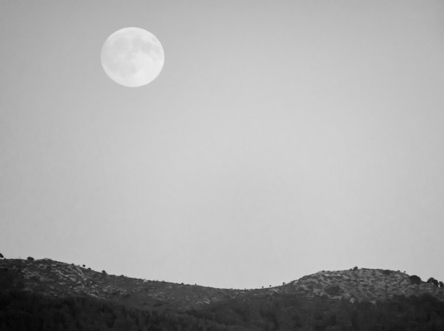 Фото Низкоугольный вид луны в горах на чистом небе