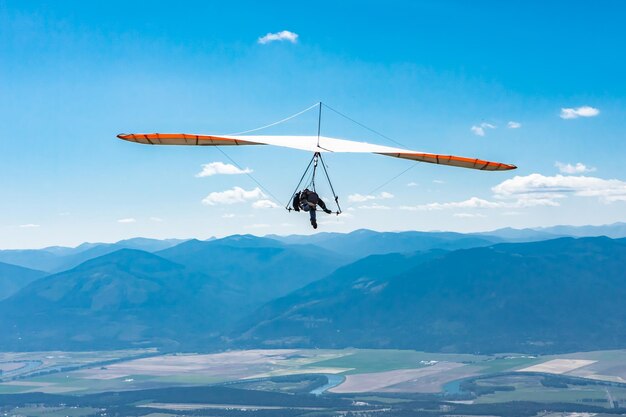 写真 空に向かって山の上をパラグライダーで飛ぶ人々の低角度の景色