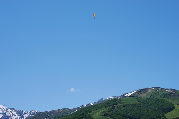 写真 晴れた青い空を背景にパラグライディングをしている人の低角度の視点