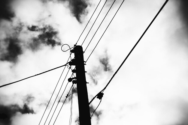 写真 雲の空に照らされたシルエット電力ピロンの低角度のビュー