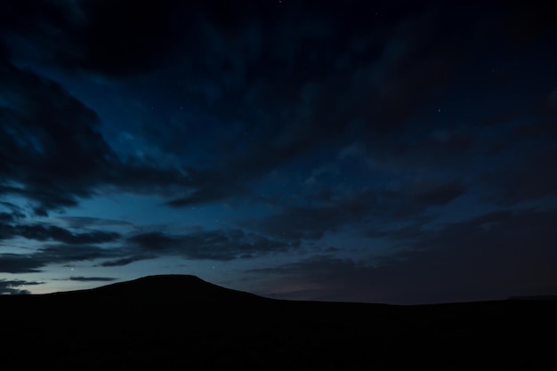 写真 夕暮れの空に照らされたシルエットの山の低角度の景色