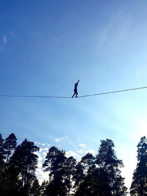 Фото Низкий угол зрения силуэта человека, идущего по веревке