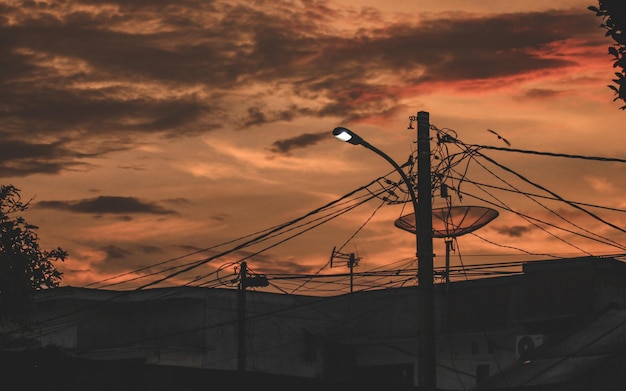 Фото Низкоугольный вид силуэтных линий электропередач на оранжевом небе