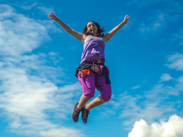 写真 青い空に向かってジャンプする女性の低角度の視点