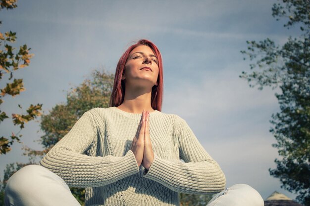 Фото Низкий угол зрения женщины, медитирующей, сидящей на небе