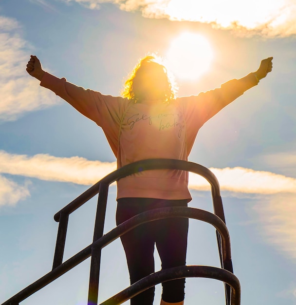 写真 夕暮れの空に照らされて海に立っている女性の低角度の写真